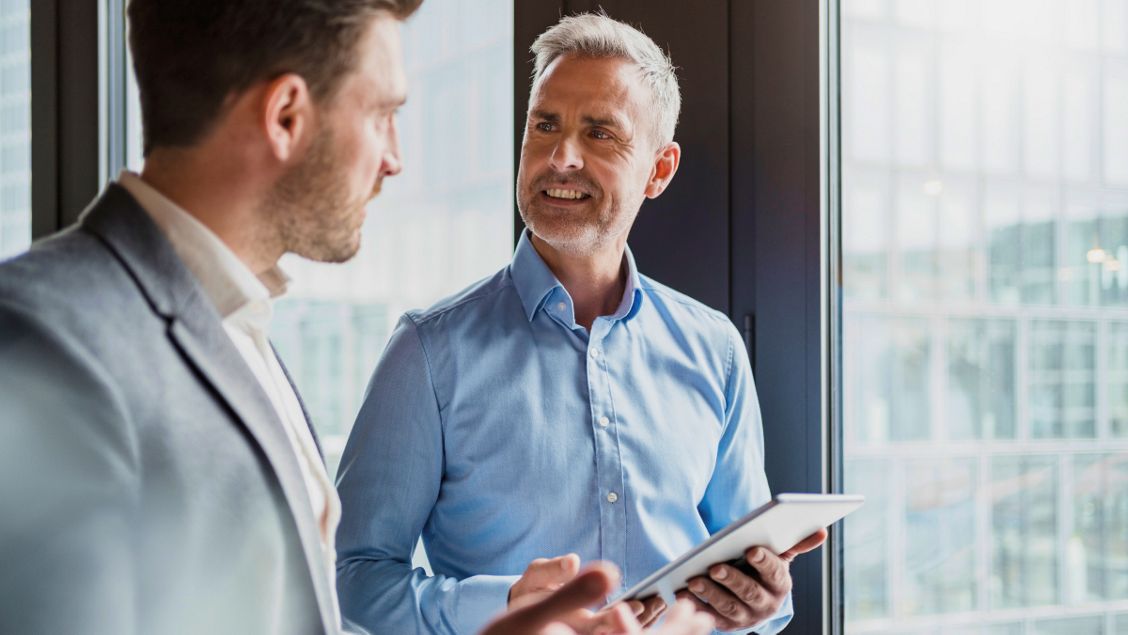 Vertegenwoordiger in gesprek met een man terwijl hij een tablet vasthoudt