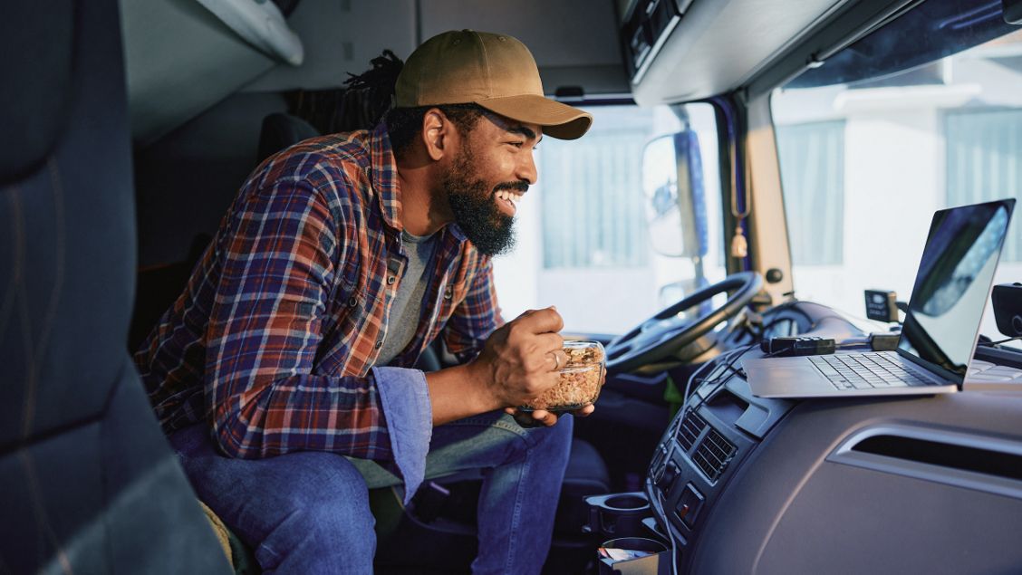Trucker in de cabine van zijn vrachtwagen met een laptop